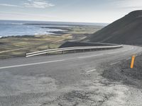 the curved road is winding over the ocean to an island of grass and rocks below