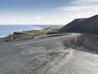 the curved road is winding over the ocean to an island of grass and rocks below