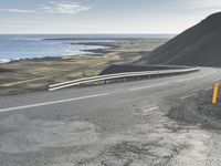 the curved road is winding over the ocean to an island of grass and rocks below