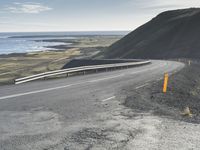 the curved road is winding over the ocean to an island of grass and rocks below