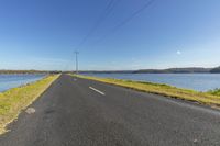 a lake with power poles across it and a road next to the water with some vegetation