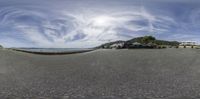 a view of the beach from a fish - eye lens with some clouds in the sky