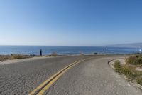 a curvy road runs along the shore of the ocean with the horizon in the distance