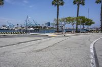 the paved street is near the harbor with no traffic on it, and in this area there's a few yellow benches along