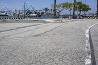 the paved street is near the harbor with no traffic on it, and in this area there's a few yellow benches along