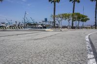 the paved street is near the harbor with no traffic on it, and in this area there's a few yellow benches along