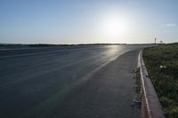 an empty road near a beach and waves as well as cars on the sand and houses on the beach