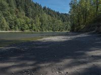 a body of water surrounded by lots of trees, near mountains and grass area with a bike parked