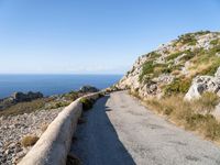 the curve road leads to an ocean view from a high cliff side overlook at rocky coastline and blue water