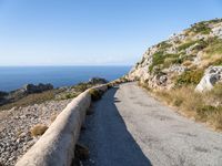 the curve road leads to an ocean view from a high cliff side overlook at rocky coastline and blue water