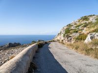 the curve road leads to an ocean view from a high cliff side overlook at rocky coastline and blue water