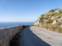 the curve road leads to an ocean view from a high cliff side overlook at rocky coastline and blue water