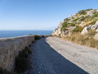 the curve road leads to an ocean view from a high cliff side overlook at rocky coastline and blue water