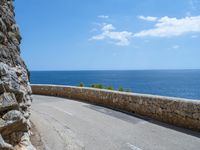 a car traveling down a road that's beside the sea in france and looks out to the ocean