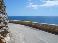 a car traveling down a road that's beside the sea in france and looks out to the ocean