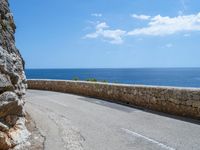 a car traveling down a road that's beside the sea in france and looks out to the ocean