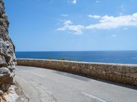 a car traveling down a road that's beside the sea in france and looks out to the ocean