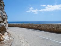 a car traveling down a road that's beside the sea in france and looks out to the ocean