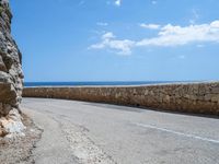 a car traveling down a road that's beside the sea in france and looks out to the ocean