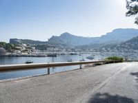 the road is going along a hillside with boats docked near it, including on to small town buildings and mountains