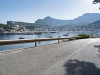 the road is going along a hillside with boats docked near it, including on to small town buildings and mountains