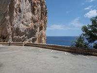 an empty parking lot near the sea on top of a steep cliff with a view of mountains