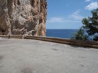 an empty parking lot near the sea on top of a steep cliff with a view of mountains