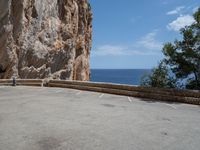 an empty parking lot near the sea on top of a steep cliff with a view of mountains