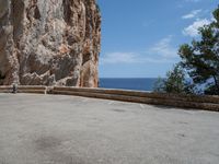 an empty parking lot near the sea on top of a steep cliff with a view of mountains