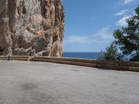 an empty parking lot near the sea on top of a steep cliff with a view of mountains