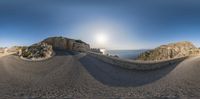 fisheye photo of road to rocky cliff top and ocean view and sky, by panning lens