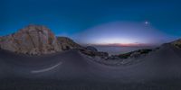 a fish - eye view of an area with rocks and a sun set on the horizon