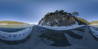 this 3d image depicts a very long road by the shore next to a mountain with ice and snow on its ground