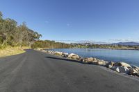 the long paved road that runs next to a lake in new zealand with rocks and boulders on both sides