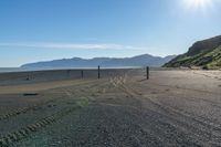 this is an empty beach that is by a body of water with mountains in the background