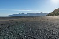 this is an empty beach that is by a body of water with mountains in the background