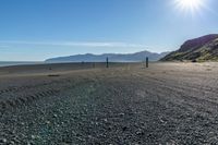 this is an empty beach that is by a body of water with mountains in the background