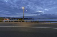 a view of the water from a nearby road at night with no one driving at the street,