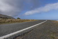 a wide view of the road and the ocean with clouds in the sky above it