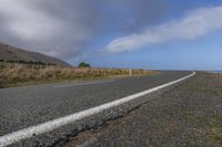 a wide view of the road and the ocean with clouds in the sky above it