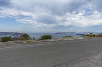 a large body of water on the side of a road near a hill and ocean