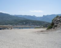 a view looking down at a large body of water from a curved road near the side of a mountain