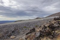 a large road with many rocks around it on the side of a hill and mountains in the distance