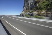 a man that is standing in the middle of a road near a cliff on top of a hill