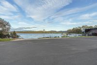 a parking lot near a lake and a boat dock with a blue sky background and clouds