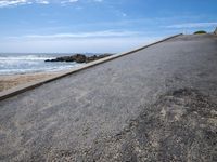the sky over a long narrow road next to the ocean on the beach, which is painted with graffiti