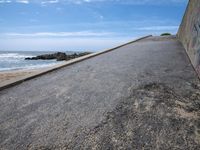 the sky over a long narrow road next to the ocean on the beach, which is painted with graffiti