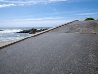 the sky over a long narrow road next to the ocean on the beach, which is painted with graffiti