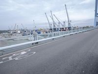 a man riding down a road with a blue bike and another motorcycle in front of a dock