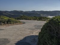 a scenic shot of the road going up hill side to the ocean on a beautiful day